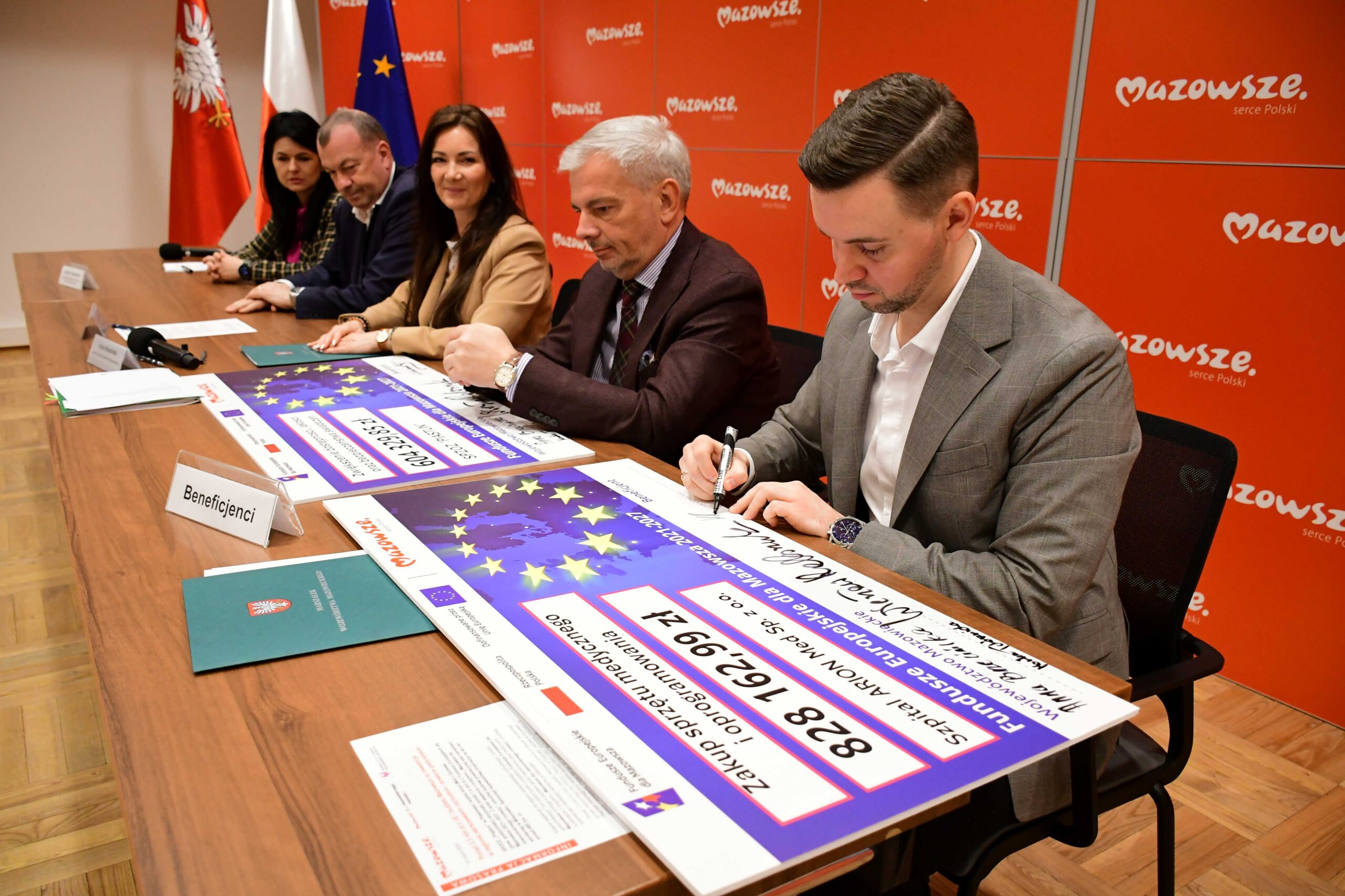 Przedstawiciel szpitala Arion Med podpisuje czek scaled